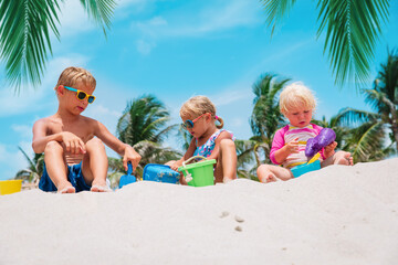 kids play with sand on beach, boy and girls on tropical vacation