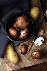 Raw mushrooms, potatoes and garlic on an old table