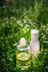 Natural organic oil, serum in bottle and hair shampoo on green grassy background
