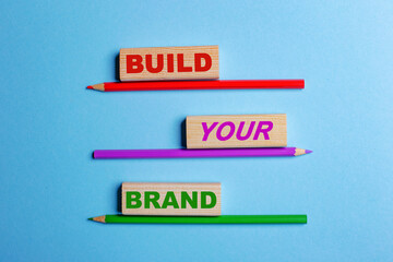 Build your brand - the inscription on the village blocks, which are stot on colored pencils on a blue background