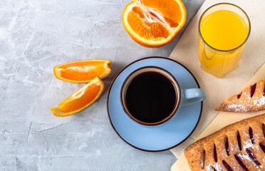 Breakfast with cup of coffee, oranges, buns and glass of juice in top view