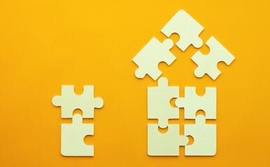 Model of a house on a uniform yellow background for the concept of real estate loans with space for text. Close-up puzzles for purchasing housing and buying on credit, and two puzzles side by side