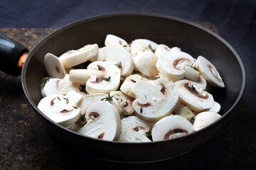 Sliced raw mushrooms with garlic, thyme, salt, ground pepper and vegetable oil in an old black skillet