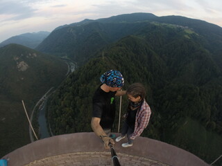 Taking an extreme selfie on top of a ruined tower, life risking extreme sports, happy couple enjoying the panorama 