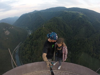 Taking an extreme selfie on top of a ruined tower, life risking extreme sports, happy couple enjoying the panorama 