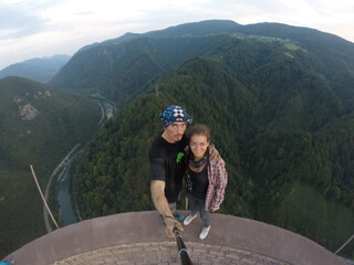 Taking an extreme selfie on top of a ruined tower, life risking extreme sports, happy couple enjoying the panorama 