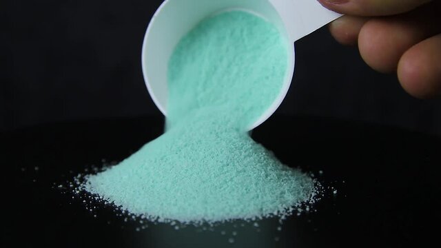 Powder are poured from a measuring spoon on a black background