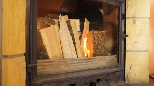 Man hand starting fire in the fireplace.Burning oak tree branch in flame. Winter heating at home on wood.