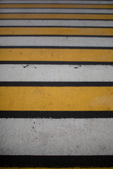 Pedestrian crosswalk-alternating white and yellow stripes on the asphalt for the safety of pedestrians on the roads