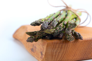 bunch of asparagus on a wooden board on a white background. horizontal orientation. front view