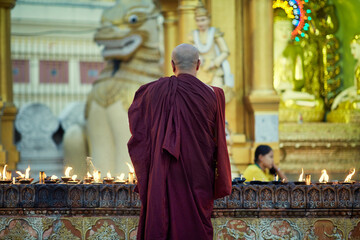 Portrait of buddhist monk lights a candles