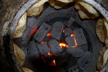 Traditional caucasian bread cooking in tandir with black coals and fire inside