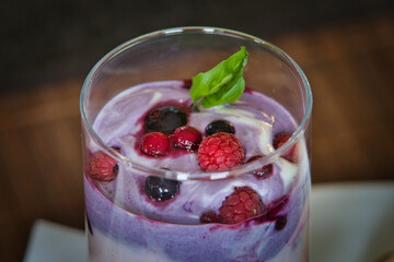 Joghurt, Pudding Dessert, Nachtisch im Glas mit Früchten, Beeren und einem Minzblatt