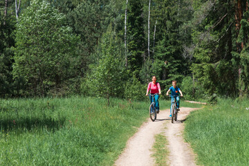 Obraz premium happy mother and son riding bikes in nature