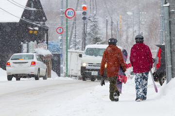 Snowboarder walking down the street to ski field.