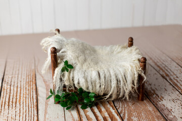 brown baby cot for a newborn photo shoot on a wooden fo. props for the photo shoot are decorated...