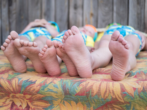 Funny children in swimsuits lie together on mattress after swimming in pool. boys are happy on vacation in village together. Summer day, river, swimming in water. Close-up of legs and feet