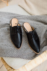 black leather shoes on female legs, a girl resting on a sofa in a blue skirt and with flowers in her hands