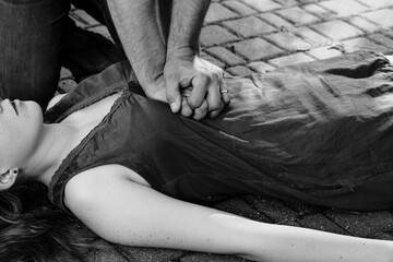 Black and white photo of man giving first aid to a woman during an street accident