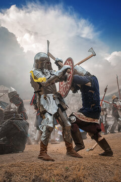 Warriors in knight armor fighting on battlefield, reenactment of medieval war