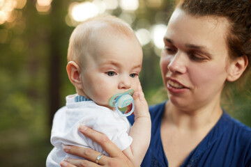 Beautiful blonde mom with he baby in forest,summer time.