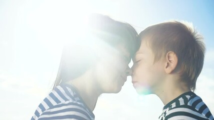son and mom cute video lifestyle concert mother's day. teamwork happy family boy kisses mother on the cheek touches his nose. parent takes care of the child. kid and adult woman mom in the sunlight at