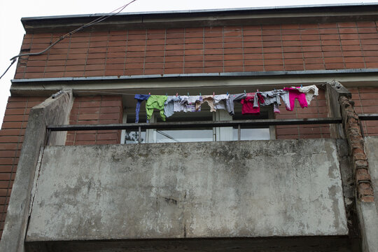 Launched baby clothes and linen are dried on the balcony of a poorly battered dormitory for family people.