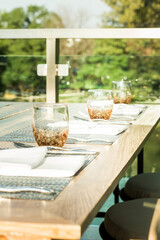 Outdoor table sitting including water glass, napkin and silver spoon fork