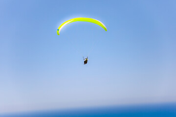 Gelber Paragleiter am blauen Himmel