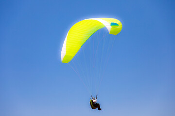 Gelber Paragleiter am blauen Himmel