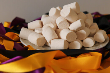 Fototapeta na wymiar The white of the marshmallows contrast with the colors of the satin ribbons composing the decoration of a beautiful table.