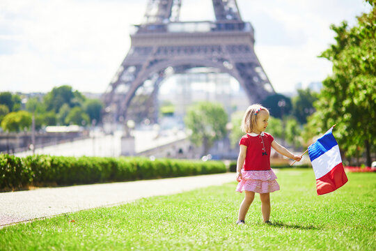 toddler girl with French national tricolor flag near the Eiffel tower in Paris, France