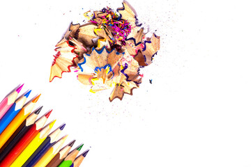 Multicolored, bright sharpened pencils in different positions on a white background. Pencil sharpener. Pencil shavings.