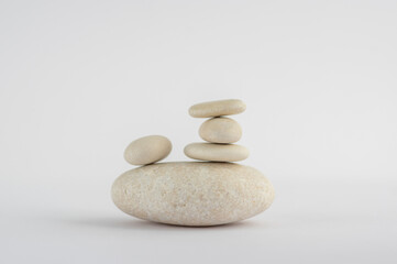 Obraz na płótnie Canvas One simplicity stones cairn isolated on white background, group of five white pebbles in tower