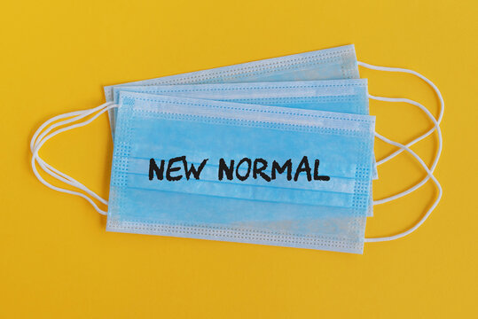 New Normal text on surgical face mask yellow background - COVID-19 concept