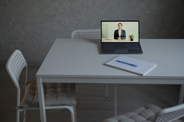 Distance Learning in Quarantine. Video conference with a female teacher on a laptop at home. Remote education during the coronavirus. Online personal tutor. Woman in a suit on a computer screen.