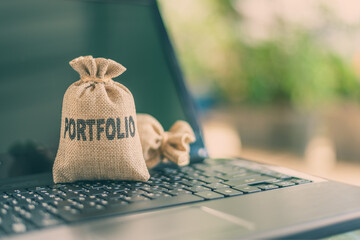 Online portfolio management for long-term sustainable growth, asset allocation and investment concept : Bags of portfolio on a laptop, depict manipulating assets for more wealth via internet from home