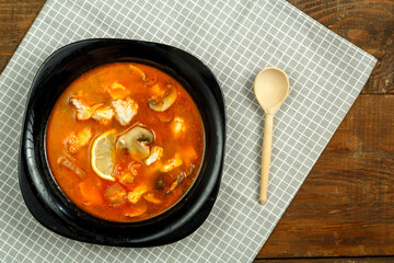 Traditional thai tom yam soup with chicken in a plate with a spoon on a linen napkin.