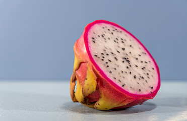 Pitaya fruit (Selenicereus setaceus) cut in half on blue background