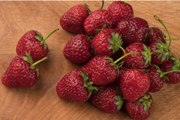 A bunch of strawberries on a wooden board