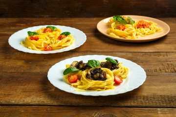 Three plates on a table pasta nests stuffed with assorted pasta paste, cheese with cherry and fried mushrooms.