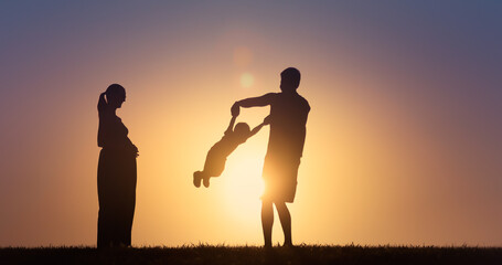 Fototapeta premium Silhouette of happy family playing together outdoors in the park.