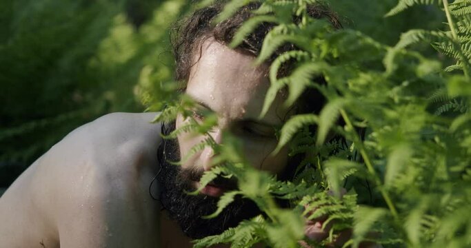close-up of the face of a naked male hermit wild man cautiously watching the sun
