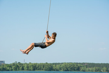 In the summer, on a bright sunny day, children ride a bungee on the lake.