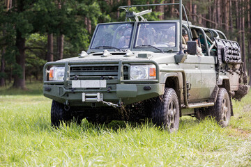 A military all-terrain vehicle travels through the countryside through puddles of mud.