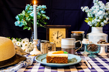 still life slice of carrot cake on blue with flowers and coffee