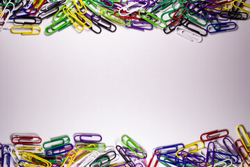 Colored paper clips for product advertising. Metal office clips attach, on a light background. Stationery fix tool for page, card. The equipment for documentation.