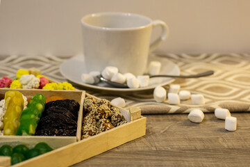 assortment of delicious nuts and dried fruits consisting of plums, peanuts in sesame seeds, dried apricots, candied fruits, kumquat and dates in a wooden package