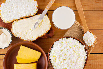 Various dairy products. Milk, cottage cheese, hard cheese and sour cream in a rustic style. Bread with cream cheese on a wooden boards. Top view