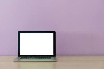 open laptop on a wooden table on a background of lilac wall in office